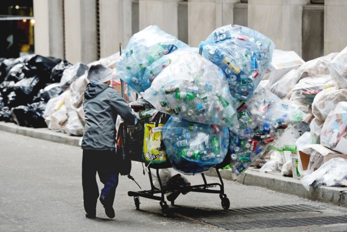 A collector of recyclable bottles and cans that can be redeemed for a cash deposit, takes advantage of the recycling that has piled up on William Street, one block from the New York Stock Exchange, Thursday, Nov. 8, 2012 in New York. Recycling pickup has been suspended in the wake of Superstorm Sandy. (AP Photo/Henny Ray Abrams)